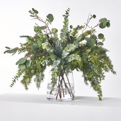 a vase filled with greenery on top of a table