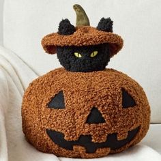 a black cat is sitting on top of a pumpkin pillow with a witches hat on it's head