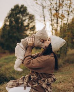 a woman holding a baby while sitting on the ground