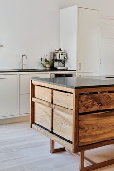 a kitchen with an island made out of wood and black counter tops, along with white cabinets