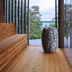 a large vase sitting on top of a wooden floor next to a glass wall with trees in the background