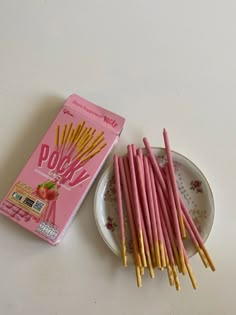 there are many pink straws on the plate next to each other and a box of pops