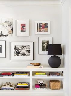 a white bookshelf with pictures on the wall and a lamp next to it