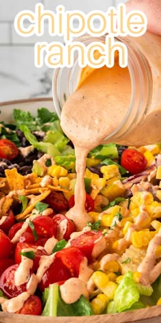 a person pouring dressing onto a salad with tomatoes, lettuce, corn and other vegetables