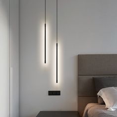 three lights hanging from the ceiling above a bed in a room with white walls and flooring