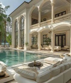 a large white house with a pool in the middle and lots of furniture around it