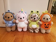 four crocheted teddy bears are lined up on the floor in front of a door