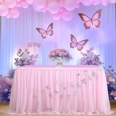 there is a table with pink flowers and butterflies on it, along with balloons in the air