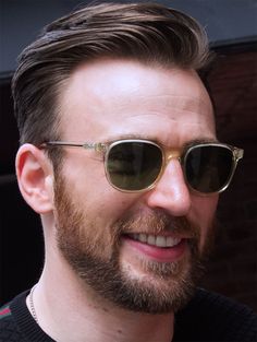 a close up of a person wearing glasses and a beard with sunglasses on his head