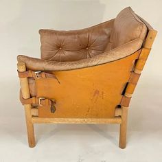 a brown leather chair sitting on top of a white floor next to a wooden frame