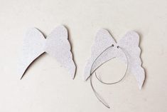 two pieces of paper cut out to look like angel wings and halos on a white surface