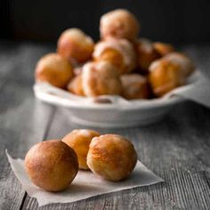 some food is sitting in a bowl on a table next to a plate with donuts