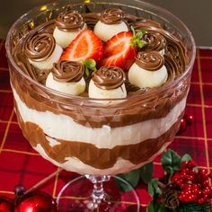 a dessert dish with chocolate and strawberries in it on a table next to christmas decorations