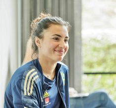 a woman sitting at a table with a laptop in front of her and smiling for the camera