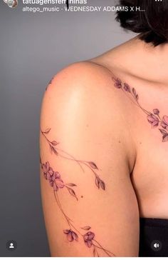 the back of a woman's shoulder with purple flowers on her left arm and chest