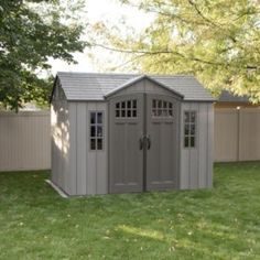 a gray shed sitting on top of a lush green field