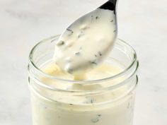 a glass jar filled with white sauce and a spoon