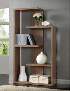 a wooden shelf with books and vases on top of it in a living room