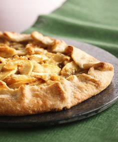 a close up of a pie on a plate with a cup in the back ground