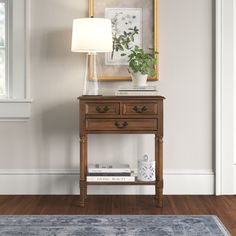 a wooden table with two drawers and a lamp next to it on top of a hard wood floor