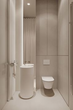 a white toilet sitting next to a bathroom sink in a room with beige walls and flooring