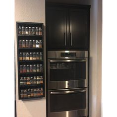 a metallic refrigerator freezer sitting inside of a kitchen next to a wall mounted spice rack