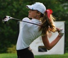 a woman swinging a golf club at a ball