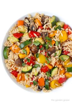 a white bowl filled with rice, vegetables and meat on top of a white table