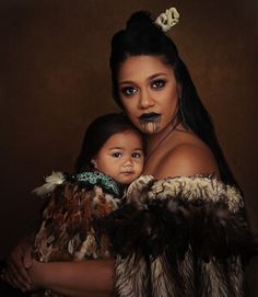 a woman holding a baby in her arms with fake makeup on their face and eyebrows