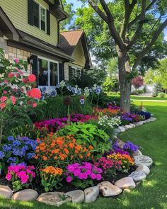 a flower bed in front of a house with lots of flowers growing on the lawn