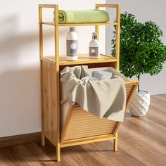 a wooden shelf with towels and bottles on it next to a potted green plant