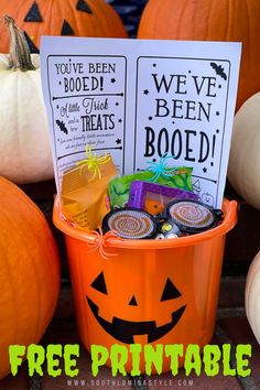 a bucket filled with halloween treats sitting on top of a brick floor next to pumpkins