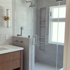 a bathroom with a walk in shower next to a sink and a mirror on the wall