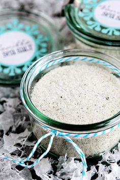 three glass jars filled with white sand on top of shredded paper