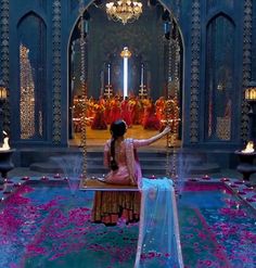 a woman sitting on a swing in front of a stage with lights and flowers all around her