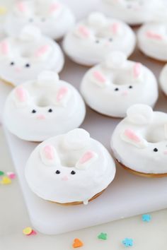 donuts with white frosting decorated as bunnies and bunny ears are on a tray