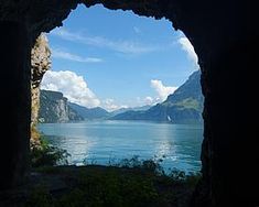 an open cave with water and mountains in the background