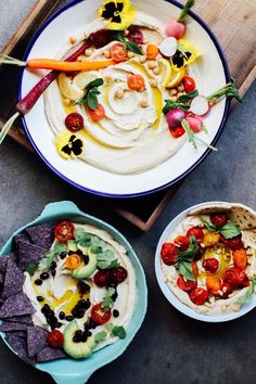 two plates filled with hummus, tortillas and vegetables