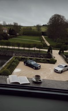 two cars parked in a driveway next to an open book