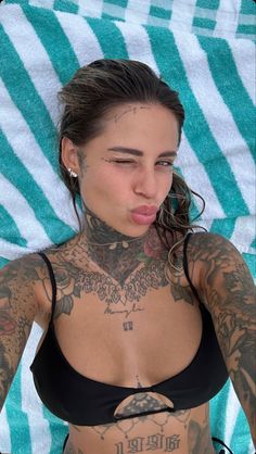 a woman with tattoos on her chest laying down