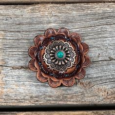 a brooch that is sitting on top of a wooden table with wood planks