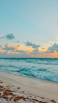 an ocean beach with waves crashing on the shore and clouds in the sky at sunset