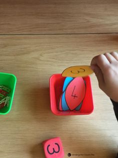 a child's hand is playing with toys on the wooden table next to it