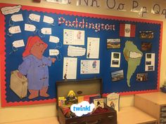 a bulletin board with pictures and writing on it in a school classroom area that has an open suitcase