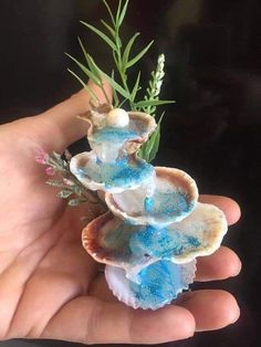 a person is holding some kind of blue and white object in their hand with plants growing out of it