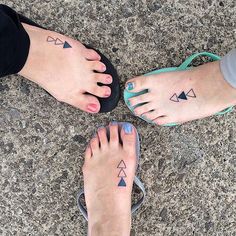 two people with tattoos on their feet standing next to each other in front of a stone floor