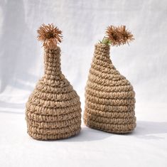 two crocheted vases with flowers in them sitting side by side on a white background