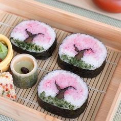 there are four sushi rolls on the tray with sauces and other food items