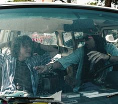 two people sitting in the driver's seat of a car talking to each other