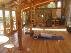 a woman is doing yoga in the middle of a room with wood floors and windows